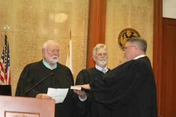 Circuit Judge Fred Koberlein Jr. (right) is sworn in Thursday by his father, Senior Judge Fred Koberlein Sr. (left), as retired County Judge Tom Coleman holds the Bible during an investiture ceremony at the Columbia County Courthouse. (TONY BRITT/Lake City Reporter)