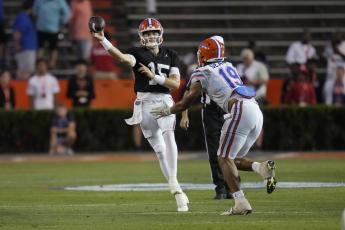 Florida quarterback Graham Mertz (left) throws a pass as he is pressured by edge T.J. Searcy (19) the team's annual Orange and Blue spring game on Thursday in Gainesville. (JOHN RAOUX/Associated Press)