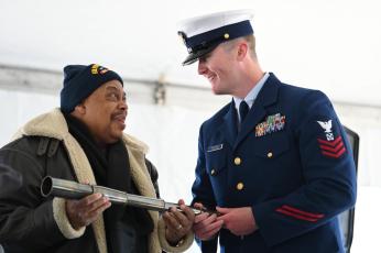 Lake City’s Marvin Deyampert, the eldest nephew of Warren T. Deyampert, presents a long glass to Petty Officer First Class Thomas Broderick of the Coast Guard Cutter Warren Deyampert (WPC-1151) during the commissioning ceremony in Boston on March 30. (Petty Officer 2nd Class Ryan L. Noel/U.S. Coast Guard)