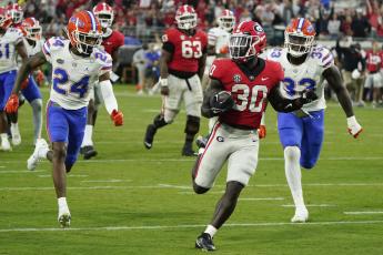 Georgia running back Daijun Edwards runs for a 22-yard touchdown past Florida cornerback Avery Helm (24) and defensive lineman Princely Umanmielen (33) during last season's 'Cocktail Party' on Oct. 29, 2022, in Jacksonville. (JOHN RAOUX/Associated Press)