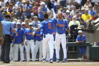 Florida outfielder Ty Evans (2) is greeted at the plate by Ben Nippolt (5) after his solo home run during the second inning of Game 2 of the College World Series finals against LSU on Sunday in Omaha, Neb. (JOHN PETERSON/Associated Press)