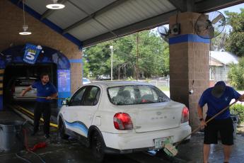 Ronald Morris (from left) and Dillon Geiger, Take 5 Car Wash general manager, prep a car with a washing session on Wednesday morning. (TONY BRITT/Lake City Reporter)