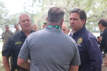 Gov. Ron DeSantis (right) talks with Suwannee County Commission Chairman Franklin White and Sheriff Sam St. John Friday afternoon in Live Oak. (JAMIE WACHTER/Lake City Reporter)