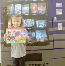 Belmont Academy kindergarten student Rylie Halks shows off her two books out of the book vending machine at the school. (JAMIE WACHTER/Lake City Reporter)