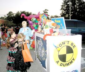 Xzailia Keown (from left), 8, checks her bag of candy as her sister, Nevaeh Keown, 9, gets candy from the DOT’s Crash Test Smarties during Tuesday night’s DOT Trunk or Treat event. (TONY BRITT/Lake City Reporter)