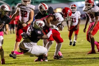 Fort White defensive lineman Christopher Smith (42) and linebacker Lecosta Byrd (11) make a tackle against Dixie County on Friday. (JACK HOWDESHELL/Special to the Reporter)