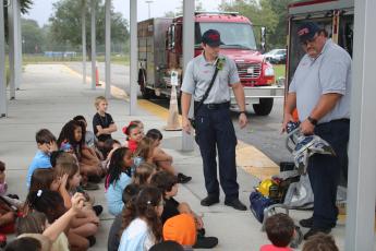 Tyler Vickery (left) and Cody Bertram, Columbia County Fire Rescue firefighters, demonstrate the Hurst Jaws of Life for Westside Elementary School second grade students for Fire Prevention Month. (TONY BRITT/Lake City Reporter)