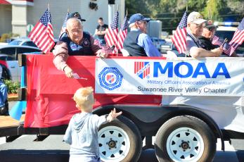 Vern Lloyd of Lake City hands a flag to a youngster who sprinted to catch up to the Military Officers Association of America float during the 2019 Veterans Day parade. (FILE)