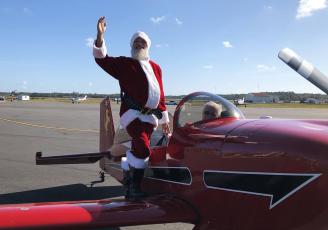 Santa Claus waves after landing in an airplane Saturday at the Lake City Gateway Airport for an event for the local Toys for Tots chapters. (COURTESY)
