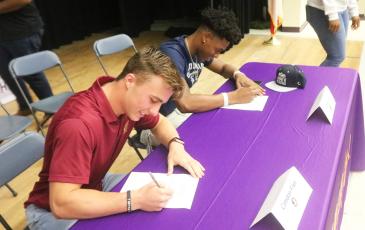 Columbia receiver Camdon Frier (left) signs his letter of intent to attend Florida State while safety Jerome Carter (right) signs his letter of intent with Old Dominion on Wednesday. (JORDAN KROEGER/Lake City Reporter)