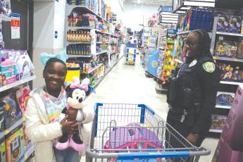 Callie Jones, 7, hugs her Minnie Mouse plush toy while shopping with Lake City Police Officer Aumaria Kelly during Wednesday morning’s Shop With A Cop event. (TONY BRITT/Lake City Reporter)