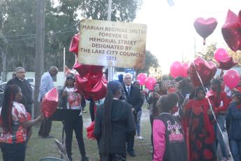 Todneisha Filer, the mother of Mariah Reginae Smith, stands amid red balloons next to the sign dedicated to her daughter’s memory Monday after she was shot and killed in August. (MORGAN MCMULLEN/Lake City Reporter)