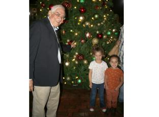 Lake City Mayor Stephen Witt (from left) stands with Aleah Hillhouse, 5, and Autumn Hillhouse while showing the youngsters ornaments on the city’s Christmas Tree during Sunday’s tree lighting ceremony. (TONY BRITT/Lake City Reporter)