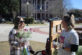 Erin Crumitie (from left) purchases a bouquet of flowers from Alyssa Roxby on Wednesday morning in Olustee Park during a Valentine's Day pop-up event for local vendors. (TONY BRITT/Lake City Reporter)