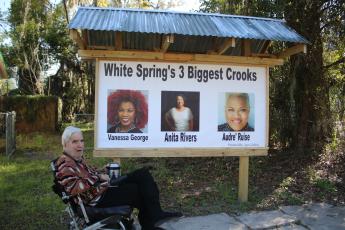 White Springs resident Joe Griffin sits in front of a sign erected on his property that calls Town Manager Vanessa George, Mayor Anita Rivers and Town Clerk Audre’ Ruise ‘crooks.’ (TONY BRITT/Lake City Reporter)