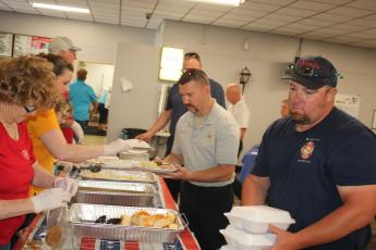 American Legion Post 57 volunteers serve meals to Columbia County Fire Rescue personnel Benjamin Fry (center) and Ronnie Crews. (TONY BRITT/Lake City Reporter)