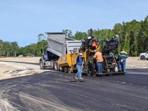 Paving crews from C.A. Boone Construction in Lake City apply smooth asphalt strips to a roadbed in the new Forest Cove subdivision on Wednesday. The new development on Branford Highway just south of Lake City features 14 one-acre lots in a rural setting and is being developed by local contractor Rob Stewart. (COURTESY)