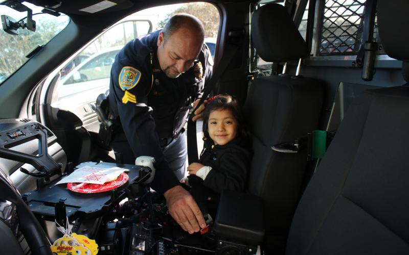 Lake City Police Department officer Robert Milligan belts in Olivia Dillow, 5, as they prepare to head out for the Lake City Police Department after a morning of shopping. (TONY BRITT/Lake City Reporter)
