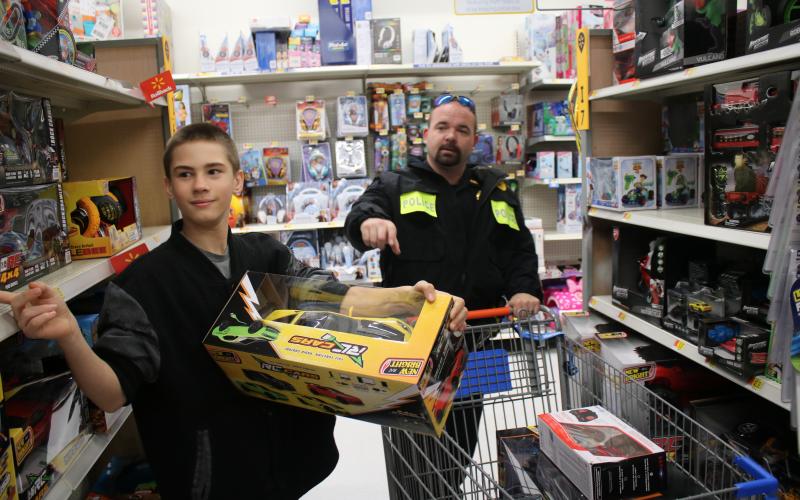 James Jordan, 13, looks over the selection of remote control cars with LCPD officer Kevin Johns during Wednesday’s Shop With a Cop event. (TONY BRITT/Lake City Reporter)