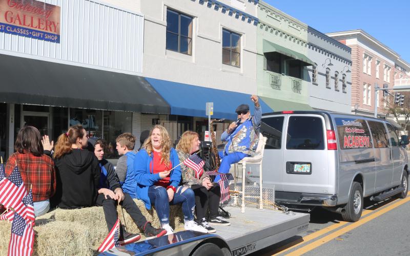 North Florida Academy of Arts and Sciences students wave American flags and smile at the crowd while taking part in the MLK Jr. parade Monday. (TONY BRITT/Lake City Reporter)