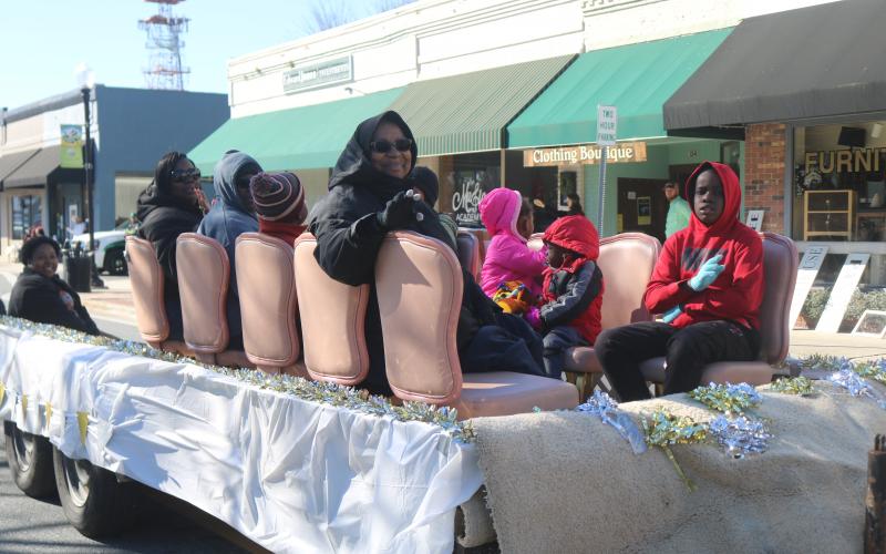 A woman waves to the crowd while riding a parade float. (TONY BRITT/Lake City Reporter)