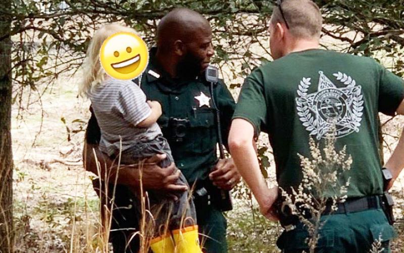 A Suwannee County deputy holds a 3-year-old who was reported missing earlier that day. The child was found in the woods, where he was under the protection of the family dog, Buddy. (COURTESY SCSO)