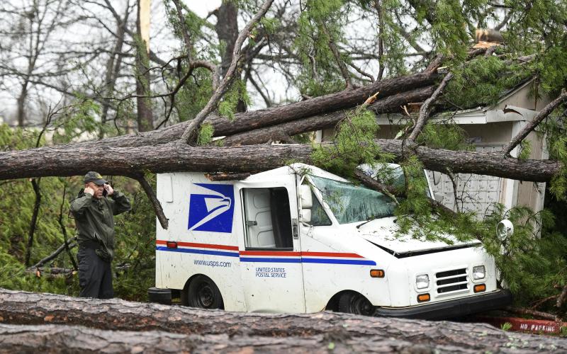 A man talks on the phone next to a damaged postal truck at an apartment complex where heavy weather passed through Thursday in Spartanburg, S.C. (SEAN RAYFORD/Associated Press)