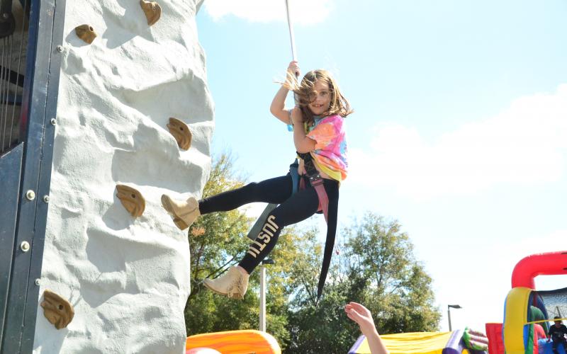 Seven-year-old Marena Kirby tries her hand at rock climbing the Olustee Battle Festival Saturday. Several other activities were also set up for the youngsters, including a bounce house. (CARL MCKINNEY/Lake City Reporter)