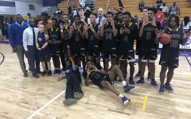 Columbia's basketball team poses with the District 2-6A title after defeating Lincoln on Saturday. (JORDAN KROEGER/Lake City Reporter)