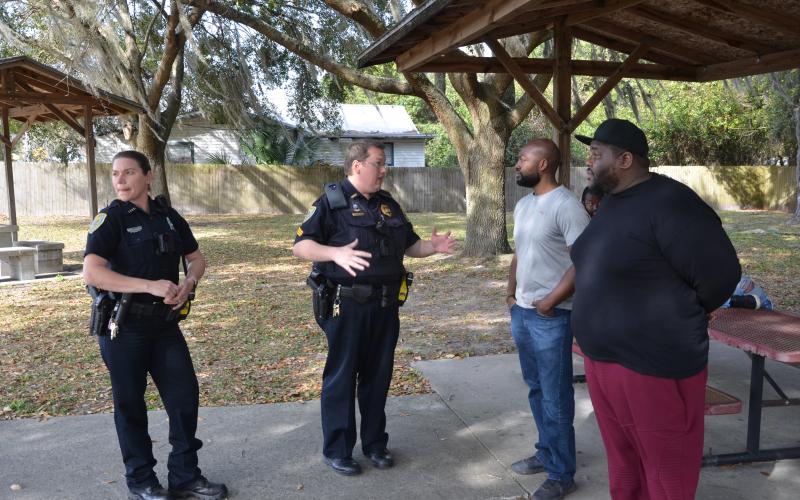 LCPD Sgt. Mike Lee speaks with Sylvester Warren and his brother, Michael Warren, after a tense exchange at a local park. Sylvester Warren gathered a group to block a public works employee from pressure washing benches, saying it would be a meaningless gesture that fails to improve the park in a meaningful way. (CARL MCKINNEY/Lake City Reporter)