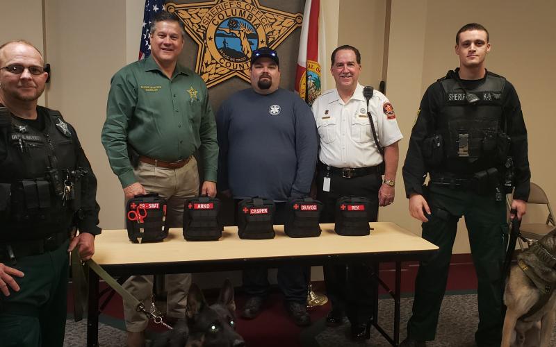 The Columbia County Sheriff’s Office accepts five K9 emergency first aid kits from Century Ambulance, the county’s EMS provider. Sheriff Mark Hunter, second-left, held a photo op with Century’s operations manager for the area, Steve Stith, pictured in the white uniform, along with K9 Drago, K9 Rek and their human counterparts. (COURTESY)