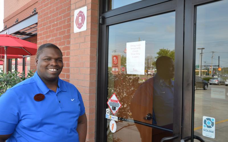 Travis Tomlin, an employee at the Lake City Chick-fil-A, stands outside the business, which has closed off its dining area to customers and gone to drive-through-only service. Other fast food chains are doing the same. (CARL MCKINNEY/Lake City Reporter)