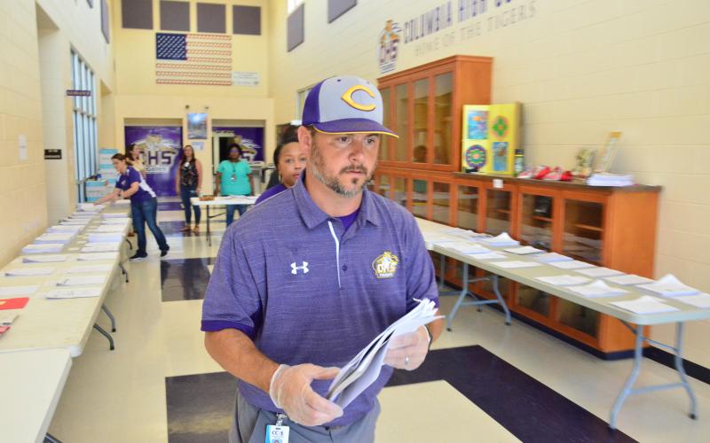 CHS Principal Trey Hosford oversees the distribution of distance-learning packets on Monday, when classes resumed following an extended spring break. Physical schools statewide are still closed to students, forcing school districts to either adopt online classes or pen-and-paper distance-learning methods. (CARL MCKINNEY/Lake City Reporter)
