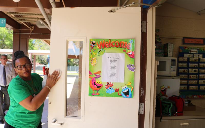 Scharlotte Stewart, Eastside Elementary School head custodian, disinfects a kindergarten classroom door on Thursday morning. The school district will have some of its employees clean and disinfect classrooms for two days next week while students and teachers are on spring break. (TONY BRITT/Lake City Reporter)