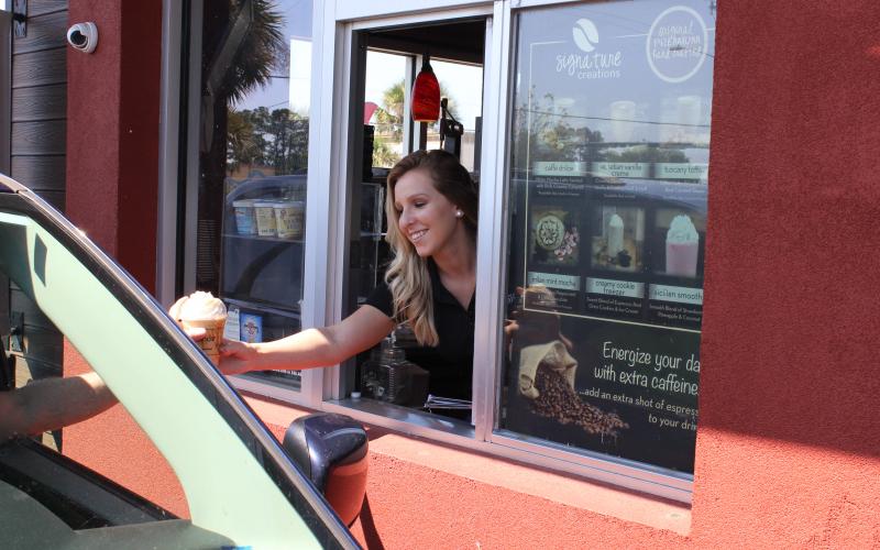 Ellianos manager Lorrain Gleason hands a custom frozen coffee creation through the drive-up window at the business location on U.S. 90 West Tuesday morning in Lake City. Ellianos serves a variety of gourmet Italian coffee and operates a double-drive-through-only business. The company, which is a Lake City-based franchise, has seen business increase during the coronavirus pandemic. (TODD WILSON/Lake City Reporter)