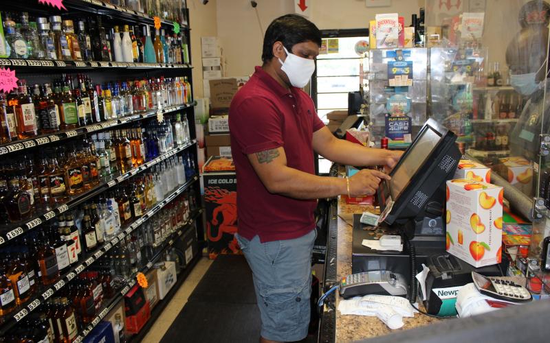 Wearing a protective mask when facing customers has become a daily part of business for Dharmendra Thakor, manager of A&D Discount Liquor in downtown Lake City. Thakor also installed a plexiglass shield at his customer service area to help protect him and his customers during the covid-19 pandemic. (TODD WILSON/Lake City Reporter)