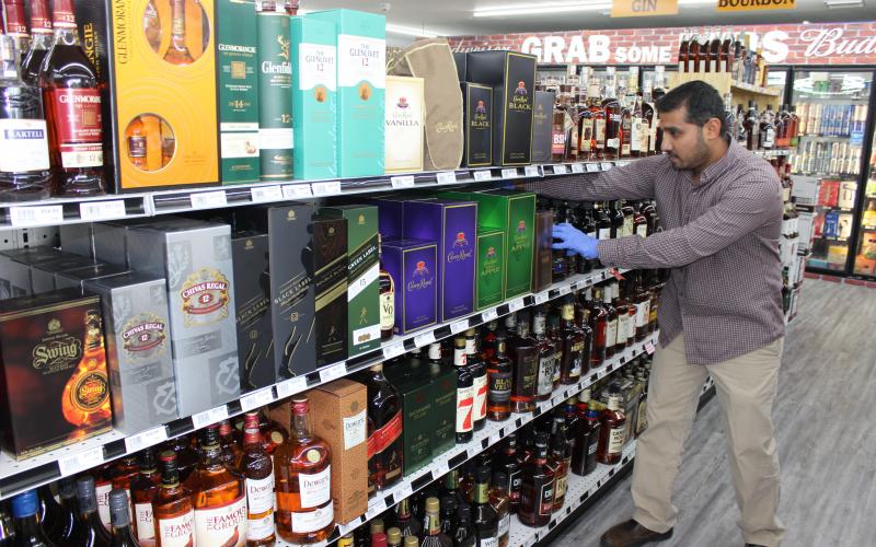 Danny Patel, owner of 47 Liquor, straightens bottles of Crown Royal on the shelves in his store in Lake City. Patel opened the new store February 1, but saw a quick spike in business when the covid-19 pandemic disrupted daily life. (TODD WILSON/Lake City Reporter)