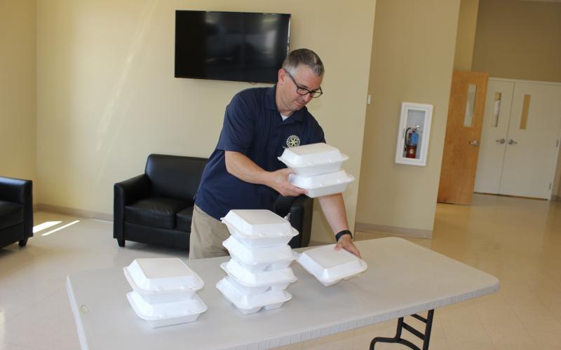 Rotary Club of Lake City Treasurer Mike Tatem stacks boxed-lunch meals at noon Thursday inside the welcome center at Parkview Baptist Church. Rotarians drove through the covered drop-off area of the church, picked up a lunch, then returned home or to their offices before tuning in to the club’s first-ever virtual meeting via the on-line platform Zoom. The club normally meets at noon on Thursdays. (TODD WILSON/Lake City Reporter)