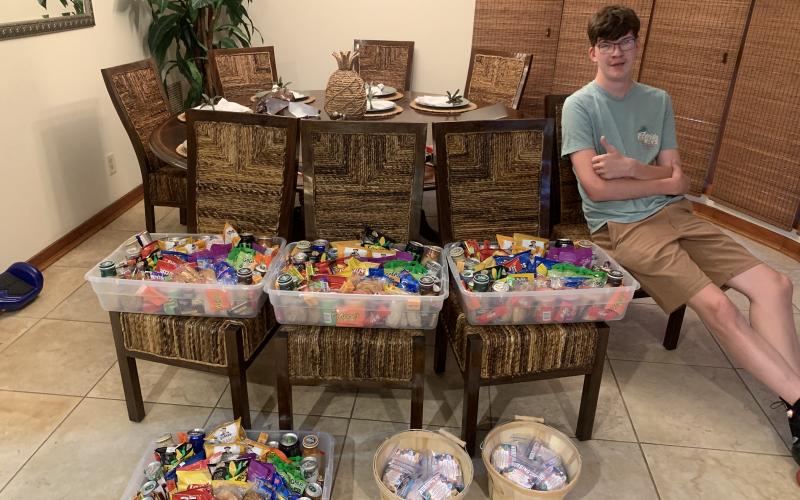 Adam Sandlin poses with baskets of chips, popcorn, sweets and whatever else he could get his hands on. The 18-year-old student at Covenant Community School had a little help raising money from his mother, who has a large presence on social media. (COURTESY)