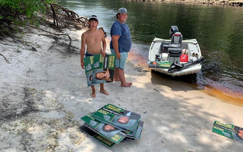 Boaters Shane McCoy and Will Griner are pictured with  the stack of signs they recovered from the Suwannee on Thursday. (COURTESY SCSO)