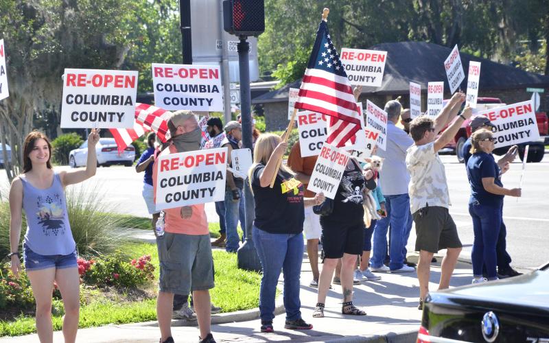 Re-open demonstrators wave signs at traffic on the corner of Duval and Marion. Among the protesters was Lisa Waltrip, a rogue hair salon owner defying the governor’s order to shut down. (CARL MCKINNEY/Lake City Reporter)