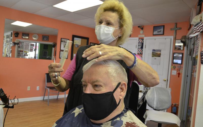 Mizz Wezzie cuts the hair of a customer, Jim Martin, who has been going to her salon for years. Miss Wezzie bought a $300 set of new blades in anticipation. (CARL MCKINNEY/Lake City Reporter)
