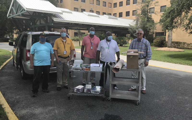 Michael Lydick (from left), Mike Carey, Karie Yates, Ben Givens and Daniel Crapps stand near carts containing an Xbox One S game console, multiple game controllers, video games, leather hobby kits, plastic model car, boat and airplane kits that were recently donated to local veterans. (COURTESY)