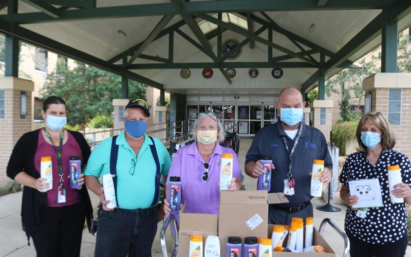 Paula Cummings (from left), stands with Michael Lydick, Stephanie Bennett, Michael Carey (Lake City VA Medical Center assistant chief of Voluntary Services) and Cynthia Voltz as they hold personal  hygiene products donated to veterans at the facility. (TONY BRITT/Lake City Reporter)