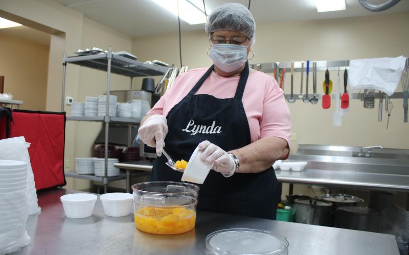 Lynda Cauley spoons up some Mandarin oranges as she prepares food at the Columbia County Senior Services Lifestyle Enrichment Center kitchen. (TONY BRITT/Lake City Reporter)