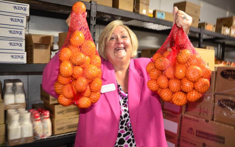 Suzanne Edwards, regional director for Catholic Charities, which operates Florida Gateway Food Bank, holds a couple of bags of oranges at the organization’s HQ on Northwest Railroad Street. (CARL MCKINNEY/Lake City Reporter)