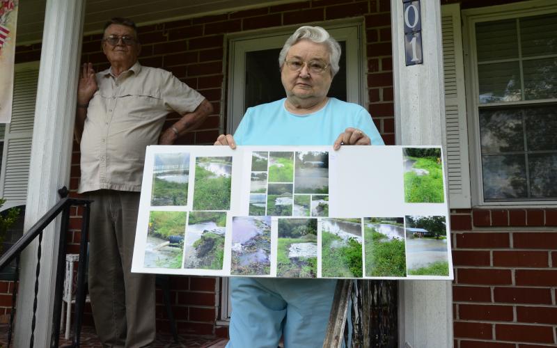 Ona and Donald Strand show pictures of the most recent flood on their property by Gwen Lake. The lakeside neighborhood’s ongoing watery woes have prompted the city to pursue a project to improve drainage in the area. (CARL MCKINNEY/Lake City Reporter)