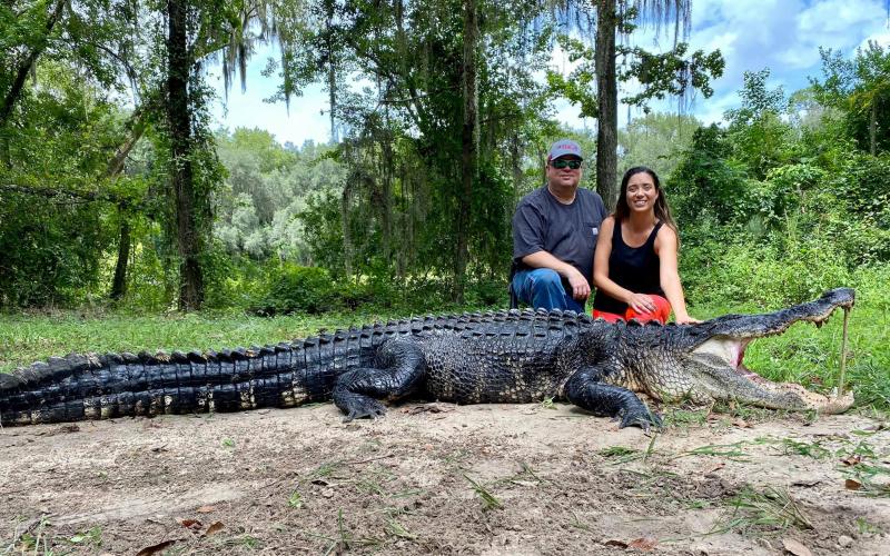 Stephen and Amy Smith with ‘Big John’ a 12-foot alligator they hunted and caught in the 15-acre pond behind their home off Lake Jeffery Road. (COURTESY STEPHEN AND AMY SMITH)