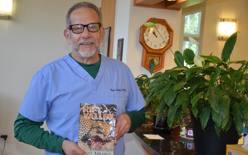 Reeve Abraben, a Lake City dentist, holds a copy of ‘Rift Valley,’ the novel he wrote and published. In addition to dentistry and writing, Abraben also is a gunsmith and is building a boat. (CARL MCKINNEY/Lake City Reporter)
