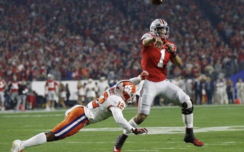 Ohio State quarterback Justin Fields, here throwing a pass while being pressured by Clemson safety K'Von Wallace in the College Football Playoff semifinal at the Fiesta Bowl in December, is among the players hoping to play college football in a safe manner this fall. (KYLE ROBERTSON/TNS)